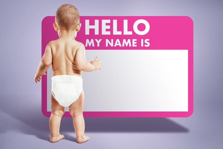 A baby standing by a "Hi, my name is" sticker.