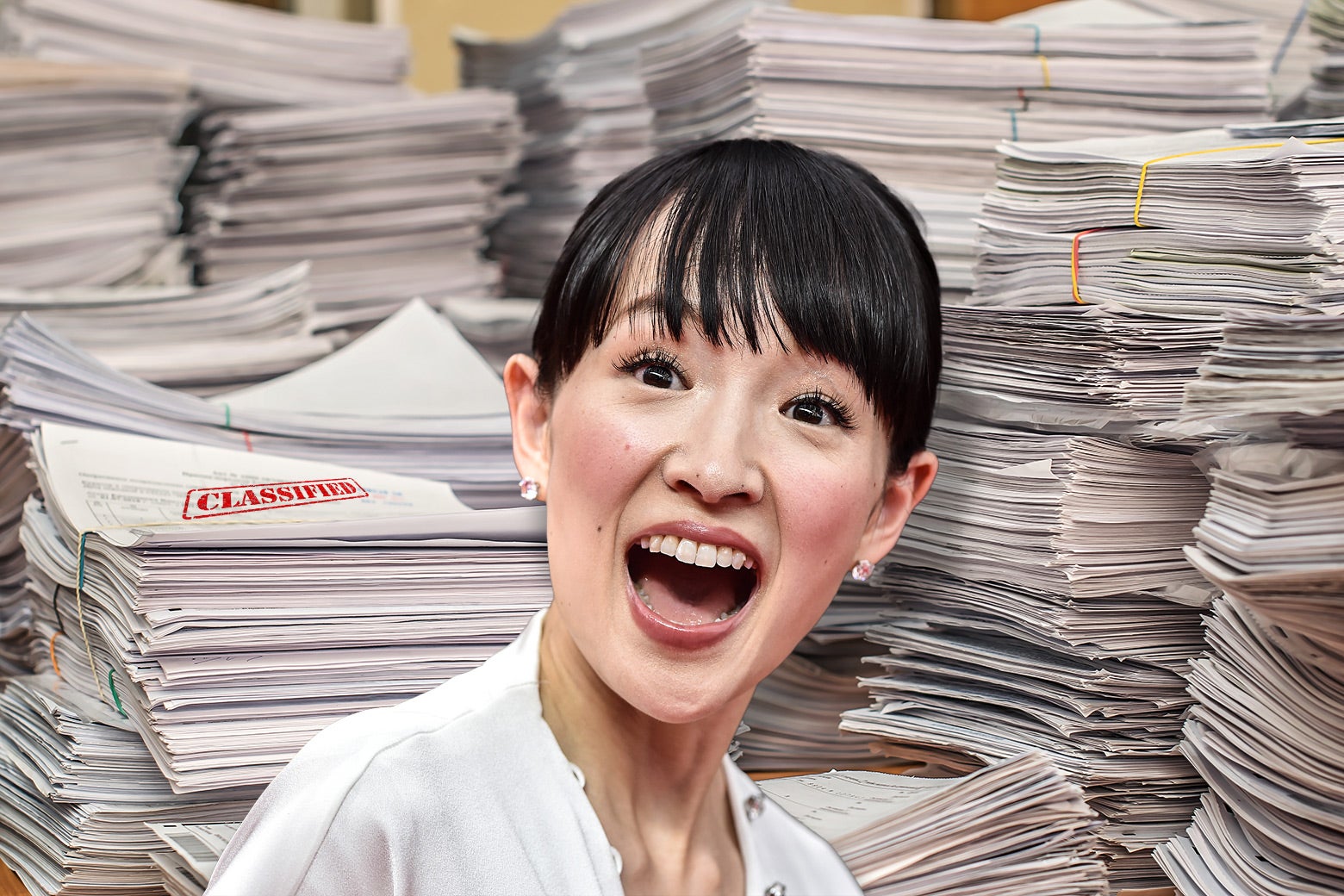 A smiling Marie Kondo in front of many stacks of classified files.