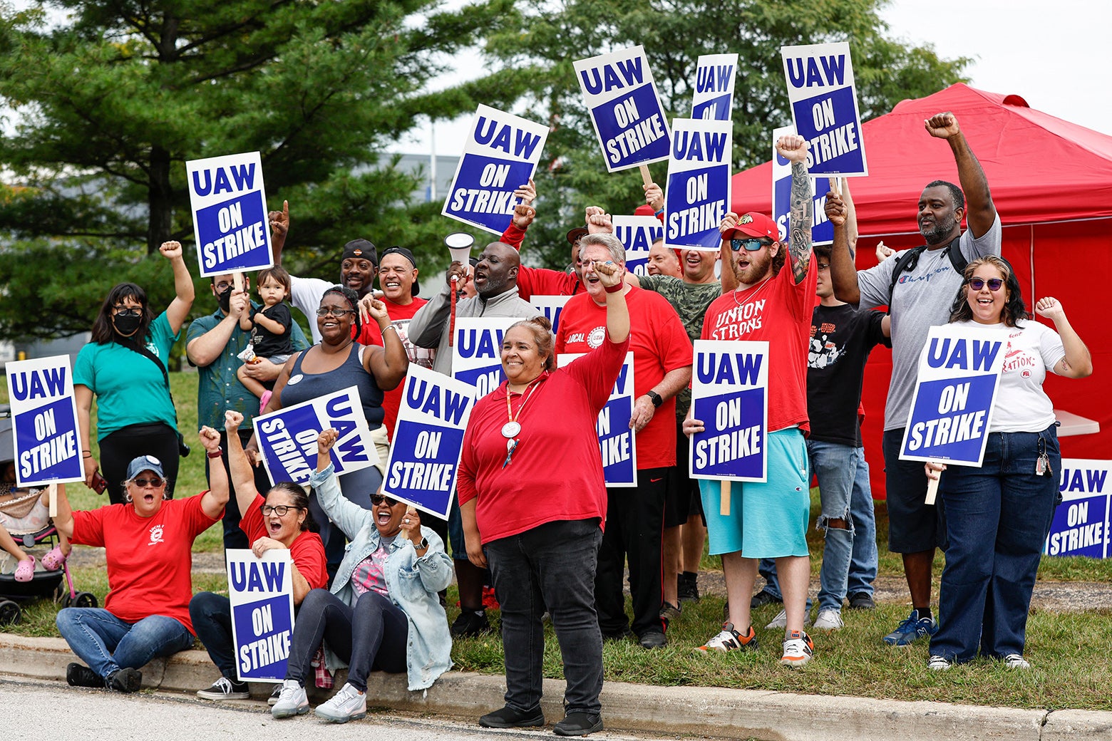 People hold up signs that say, "UAW on strike."