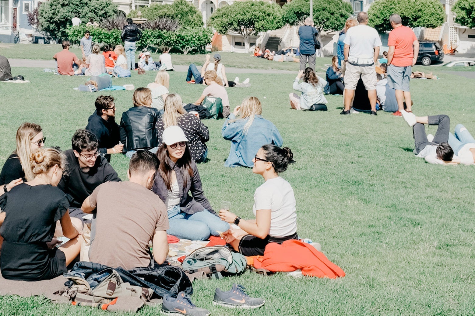 Groups of people sitting on blankets at a park.