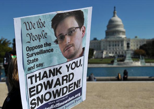 Demonstrators hold placards supporting former US intelligence analyst Edward Snowden during a protest against government surveillance on October 26, 2013 in Washington, DC. 