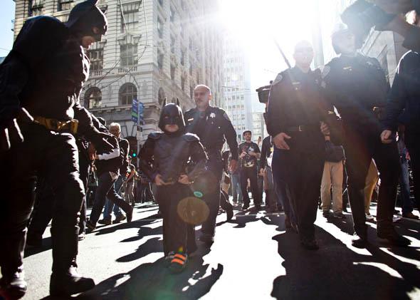 Police escorts 5-year-old leukemia survivor Miles, also known as BatKid and Batman after they arrest the Riddler November 15, 2013 in San Francisco. 