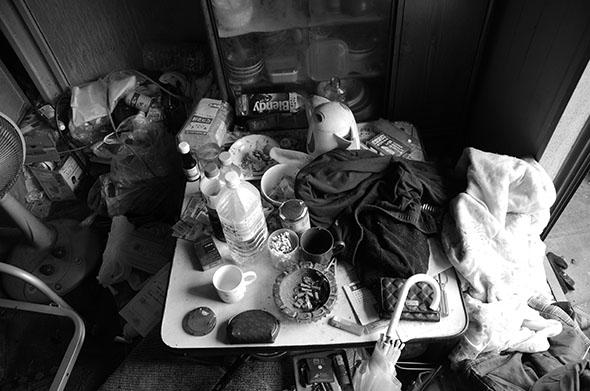 A table full of Watanabe's abandoned possessions, cigarettes and half-eaten food. The room is littered with these shrines to domestic irresponsibility.