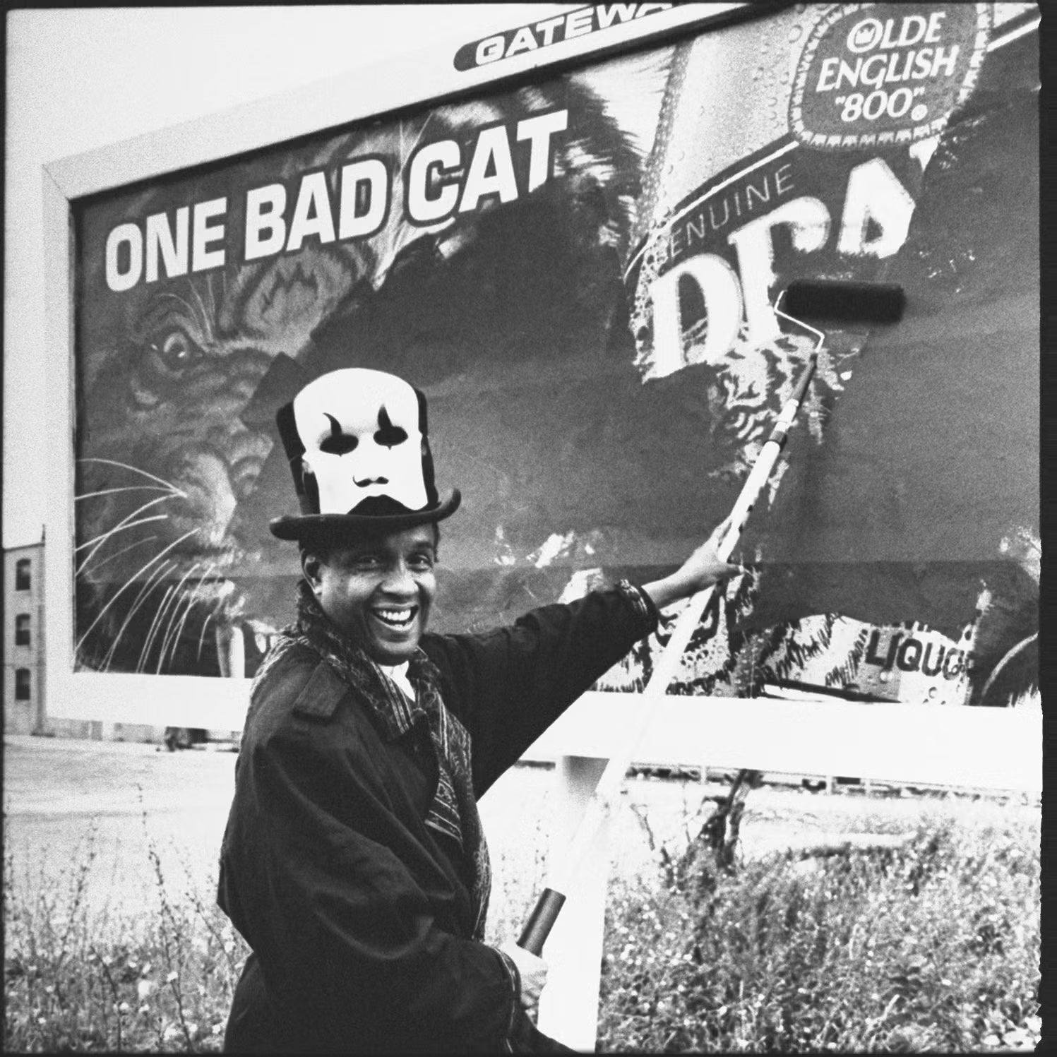 Archival photo of a man with a paint roller painting over a billboard advertising cigarettes.