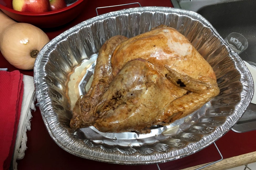 A yellowish turkey in a foil roasting pan.