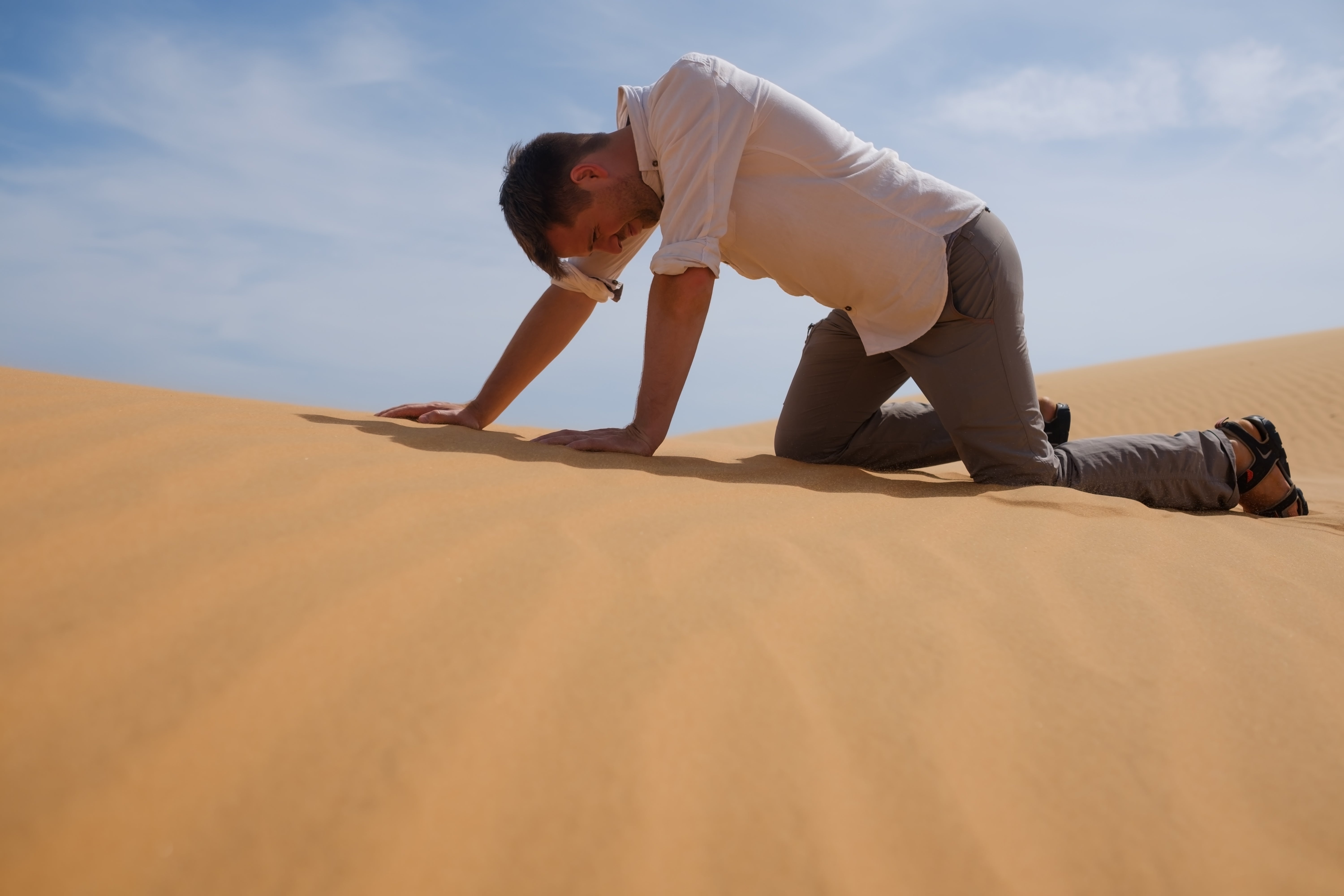 Man crawling on hands and knees in the desert