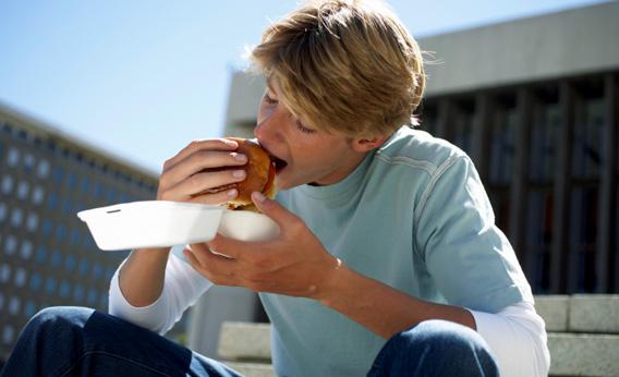 Teenage boy eating a hamburger.